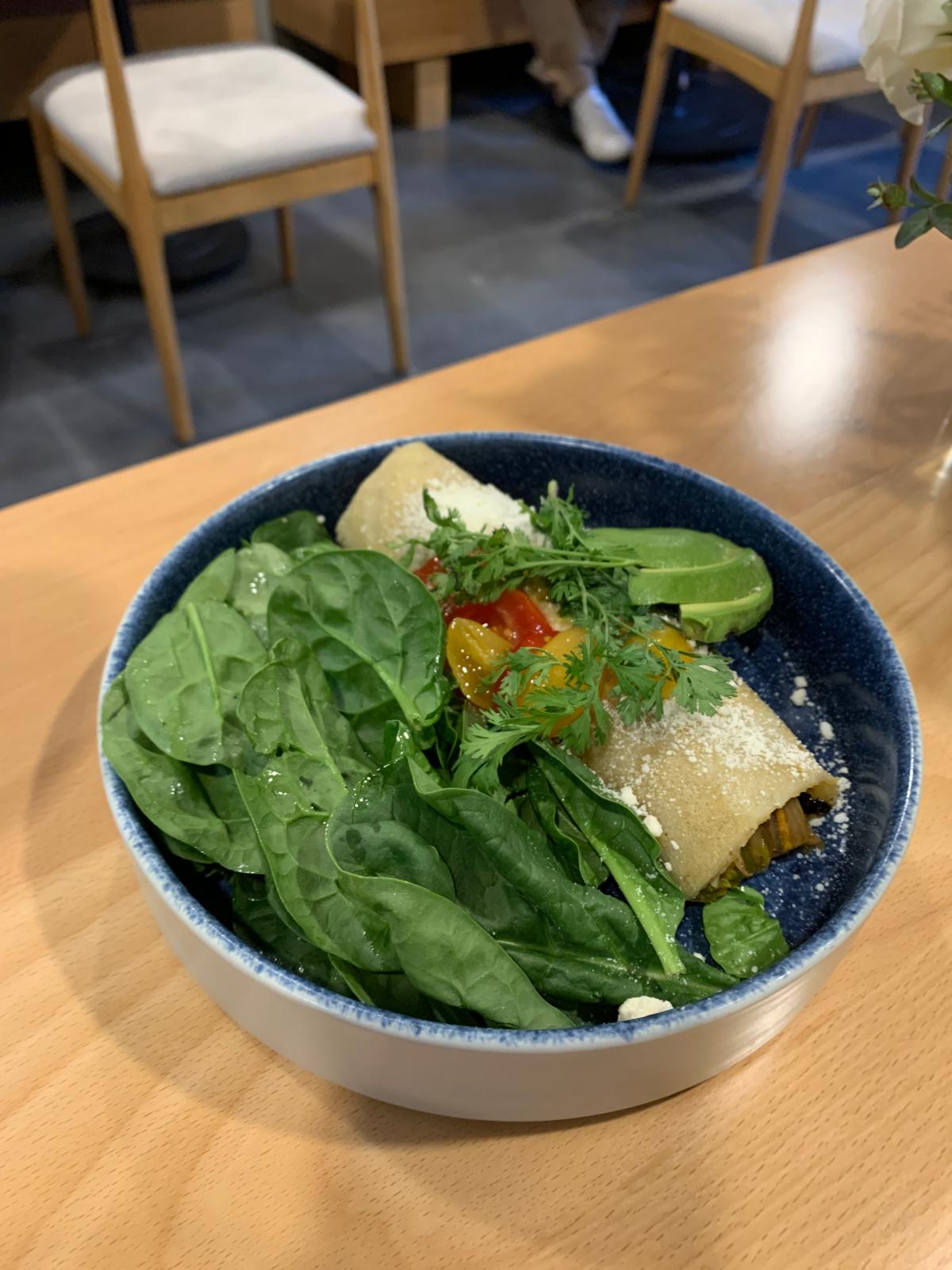 A rolled crepe with baby spinach salad on the side